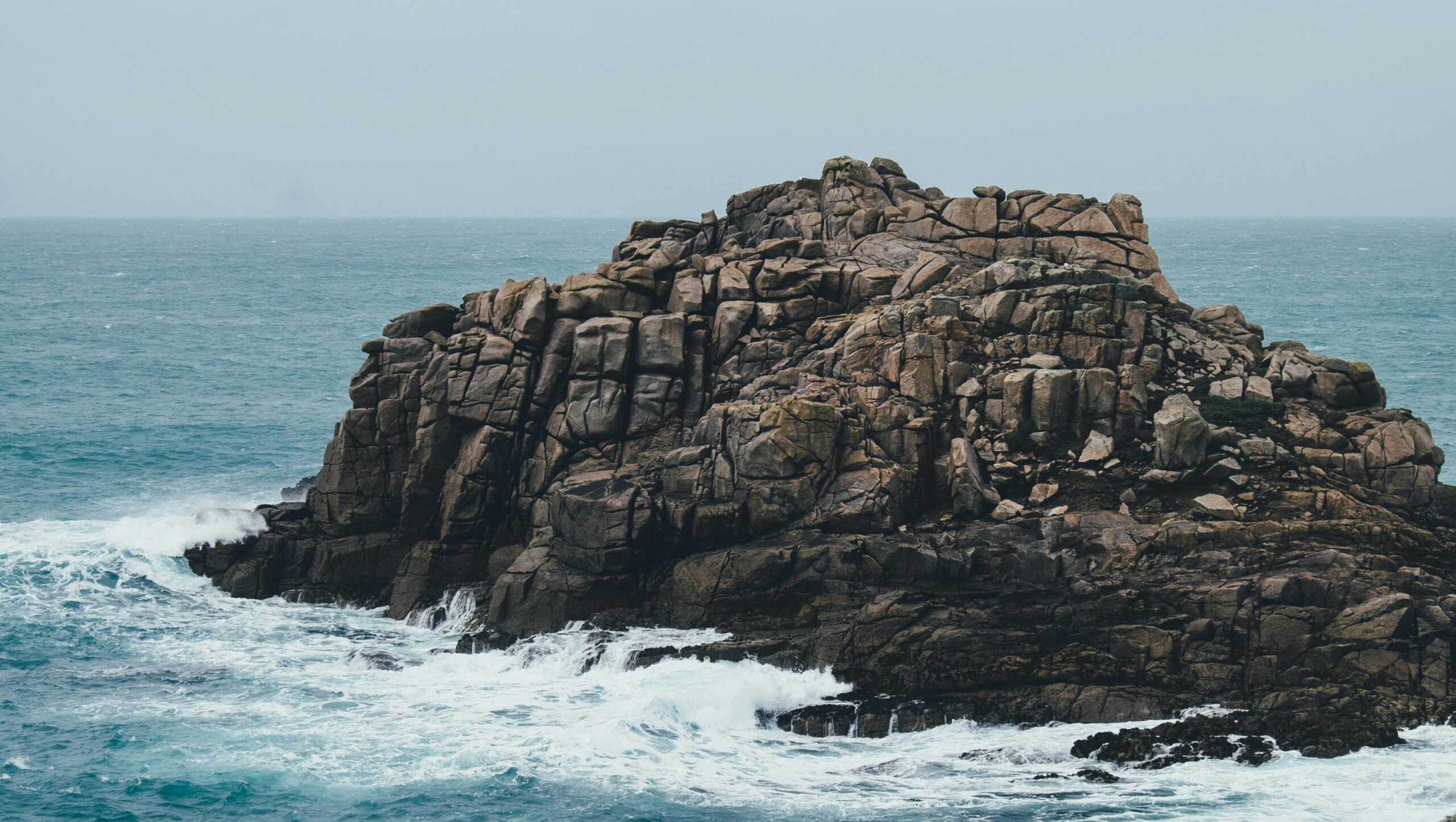 A tiny rock island surrounded by waves